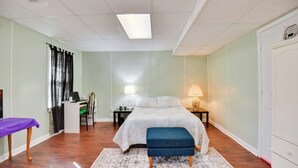 A bedroom with a bed, desk, chair, and a small table with a lamp.