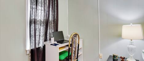 A room with a desk, a chair, a lamp, and a window with curtains.