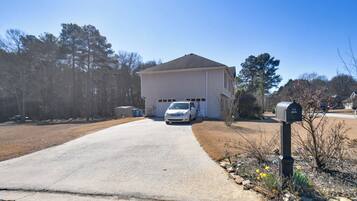 A single-story house with a driveway leading to the front door, a mailbox, and a parked car.