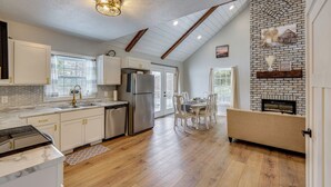 A modern kitchen with white cabinets, a stainless steel refrigerator, and a brick fireplace. - Willard Home On Working Farm w/ Water Views! (Willard)