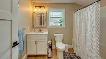 A bathroom with a white sink, toilet, and shower curtain.