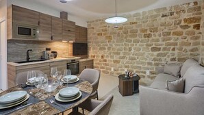Una cucina moderna con una parete in pietra, un'area pranzo con tavolo in marmo e un divano grigio.