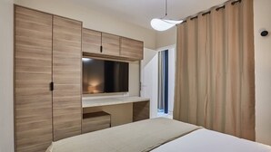 Una camera da letto con un letto, una TV, un armadio e una tenda.