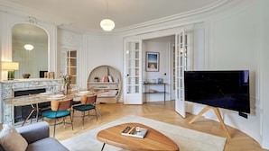 Una sala de estar amplia con chimenea de mármol, comedor, televisor y una zona de estar acogedora.