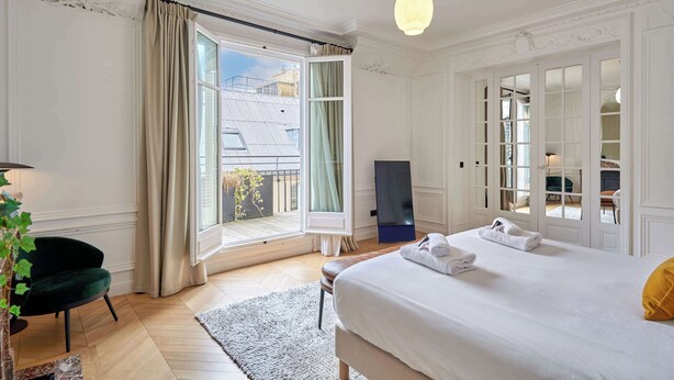 Un dormitorio con una cama grande, una ventana con cortinas, un escritorio y una silla.