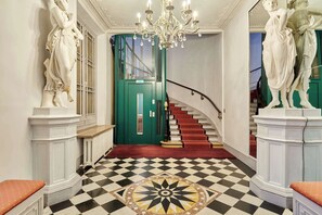 A grand hallway with a checkered floor, a green door, and a staircase with red steps. - Wonderful AC Apartment Terrace Madeleine Opera (Paris)