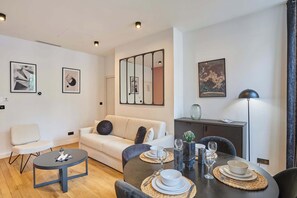 Ein modernes Wohnzimmer mit einer Couch, einem Couchtisch und einem Essbereich mit Tisch für zwei Personen.