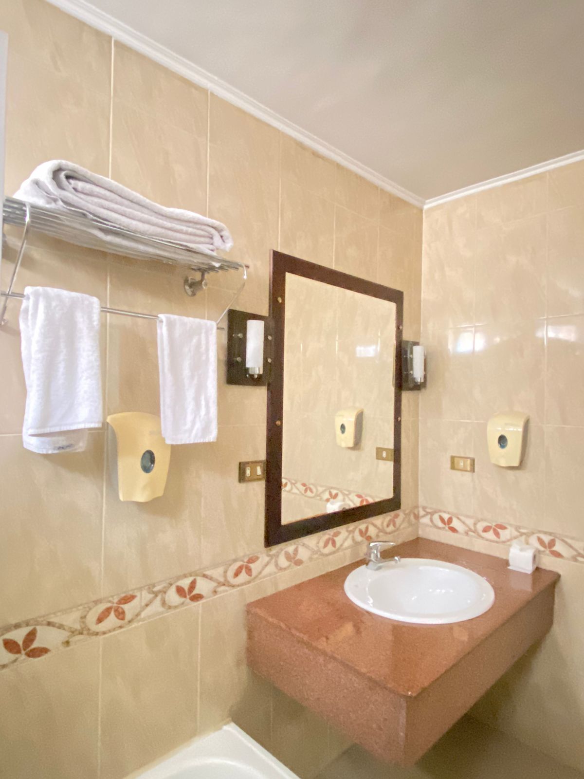 A bathroom with a sink, mirror, towel rack, and a bathtub.