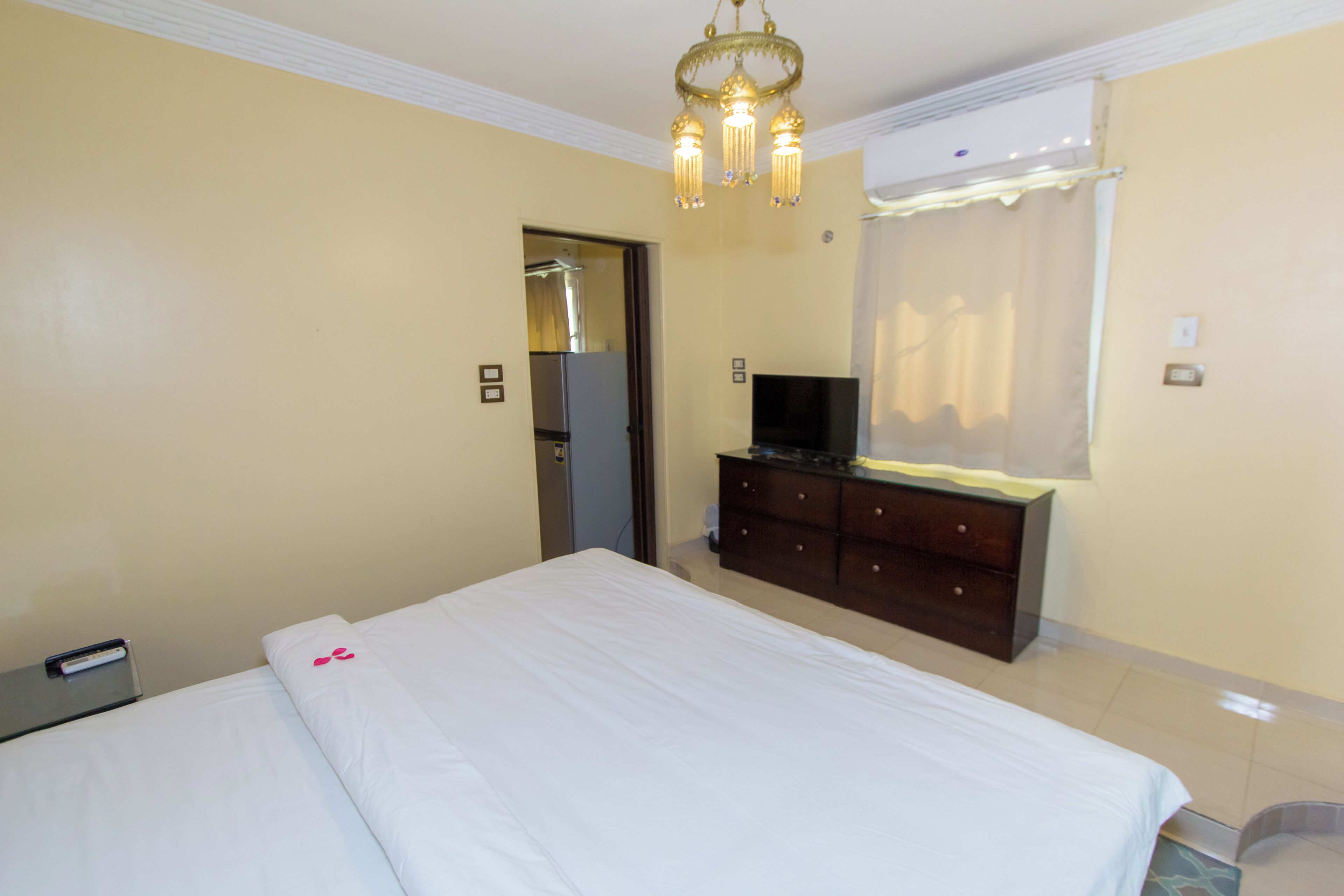 A hotel room with a bed, a dresser, a television, and a door leading to a bathroom.