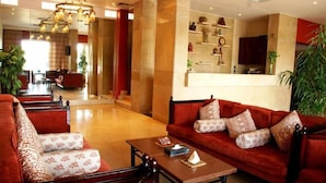 A spacious lobby with a red sofa set, a coffee table, and a chandelier. - Philae Hotel (Aswan)