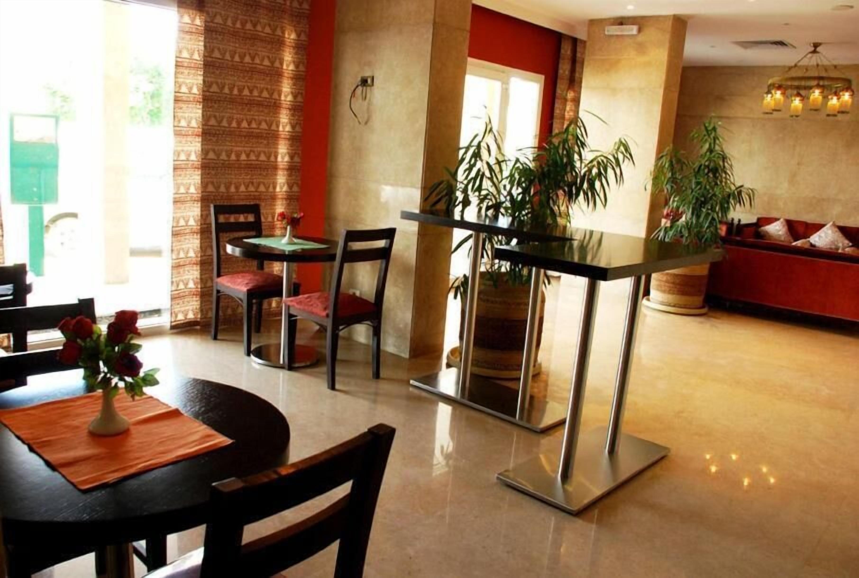 A hotel lobby with a reception desk, seating area, and a large potted plant.