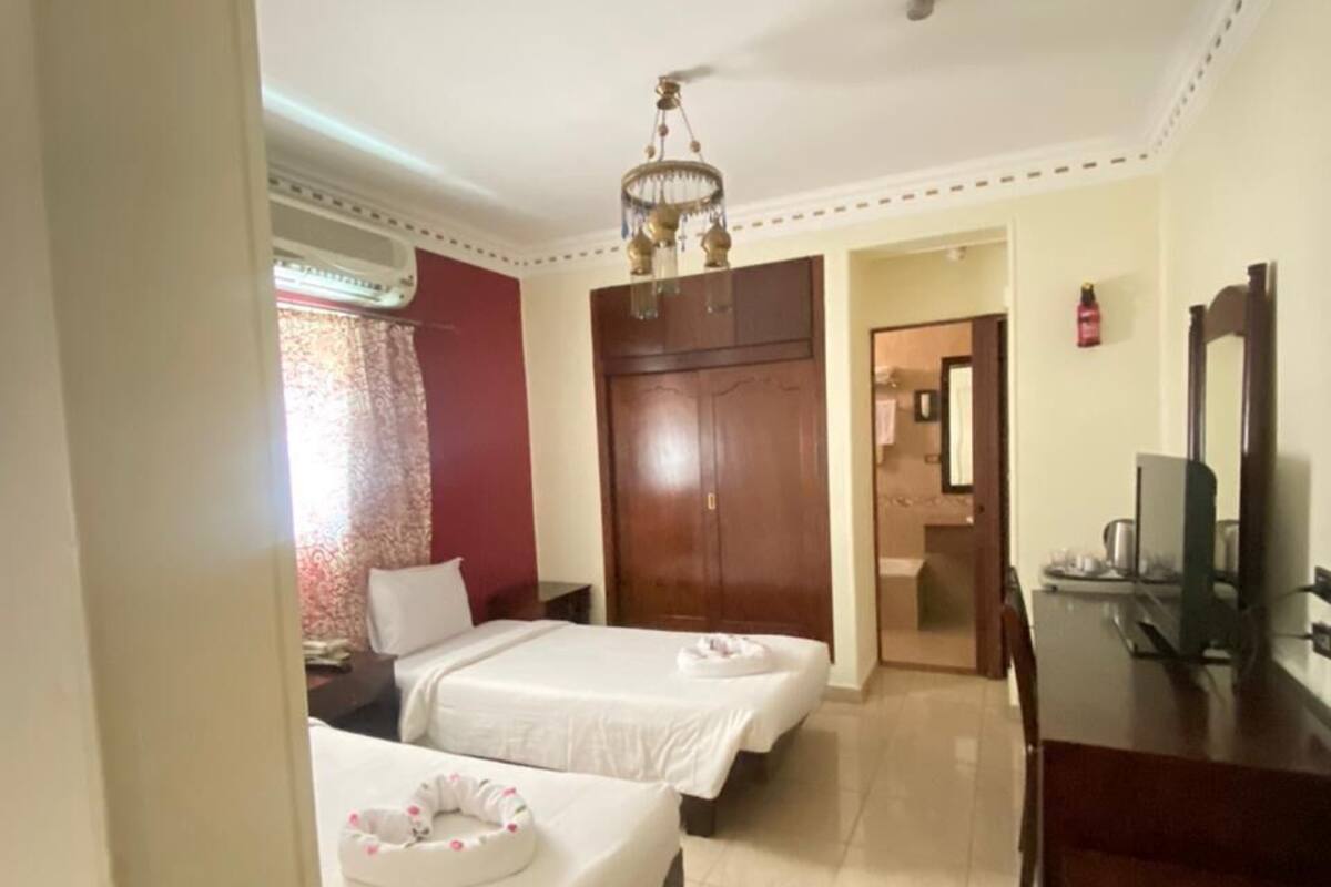 Een hotelkamer met twee bedden, een bureau, een televisie en een badkamer die door een open deur zichtbaar is.