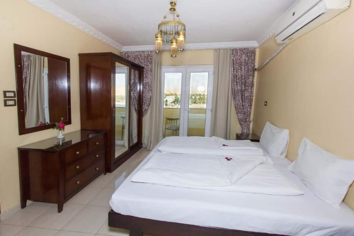 Een hotelkamer met een groot bed, een kaptafel, een spiegel en een kroonluchter.