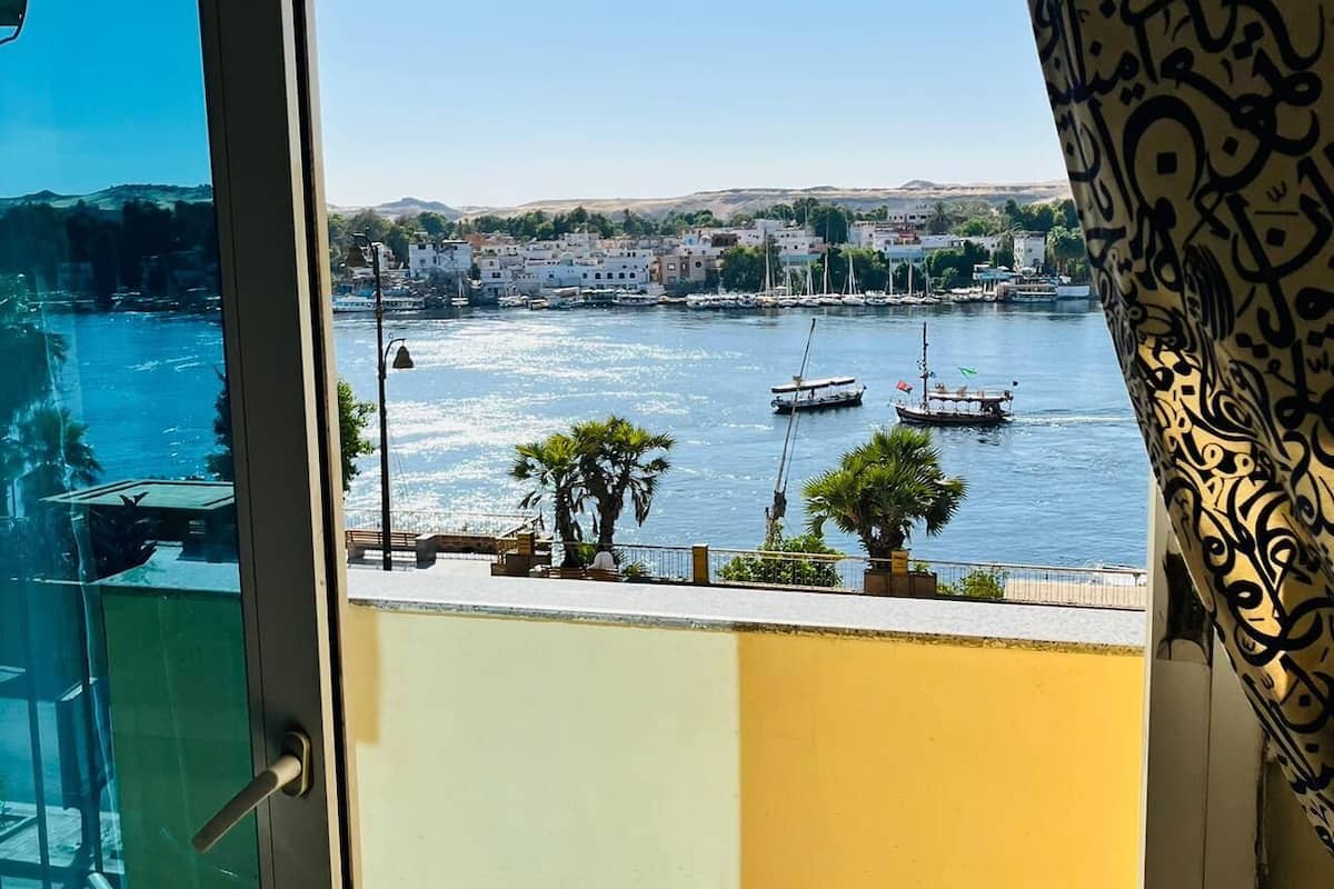 Uitzicht vanaf een balkon op een haven met boten, palmbomen en gebouwen op de achtergrond.