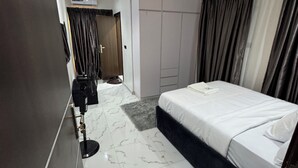 A modern hotel room with a bed, a desk, and a wardrobe.