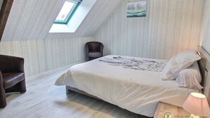 A bedroom with a skylight, a bed with a floral bedspread, a chair, and a nightstand with a lamp. - House sleeps 7, 10 minutes walk from the beach Pets welcome (Plurien)