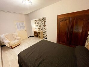 A room with a bed, a chair, a desk, and a wardrobe.
