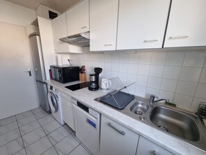 A compact kitchen with white cabinets, a microwave, a coffee maker, and a sink. - Family Apartment with Air Conditioning and Parking in Collioure (Collioure)