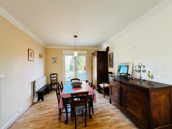 A dining area with a wooden table and chairs, a radiator, and a cabinet with decorative items.