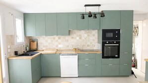 Una cucina compatta con mobili verdi, lavastoviglie, forno a microonde e fornello.