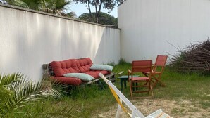 Un'area patio con un divano rosso, una sedia di legno e una poltrona da esterno a righe.