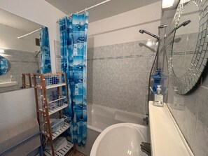 Ein Badezimmer mit Badewanne, Dusche und Ablage für Pflegeprodukte.