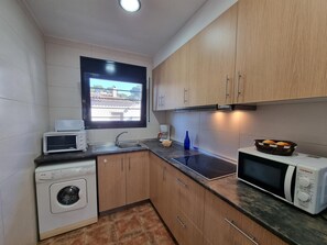 A compact kitchen with a washing machine, a microwave, and a coffee maker. - Charming house near the beach in L’Escala (L'Escala)