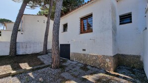 A white building with a stone base, a small window with wooden shutters, and a door. - Charming house near the beach in L’Escala (L'Escala)