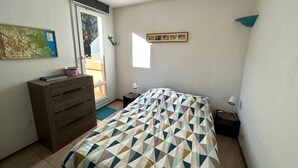 A bedroom with a bed, dresser, and a window with a view. - Argelès-sur-Mer: Cozy 4-person apartment with terrace, near the beach (Argelès-sur-Mer)