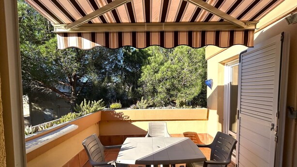 An outdoor patio with a table and chairs, surrounded by a wooden pergola and a view of trees. - Argelès-sur-Mer: Cozy 4-person apartment with terrace, near the beach (Argelès-sur-Mer)