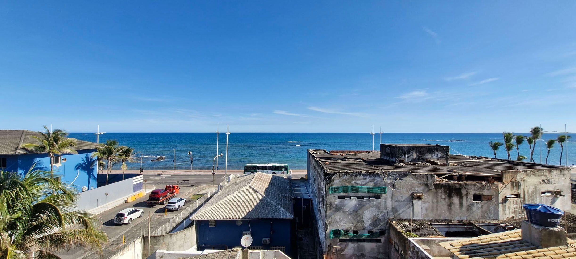 Une zone urbaine côtière avec des bâtiments, une route et une vue sur la mer.