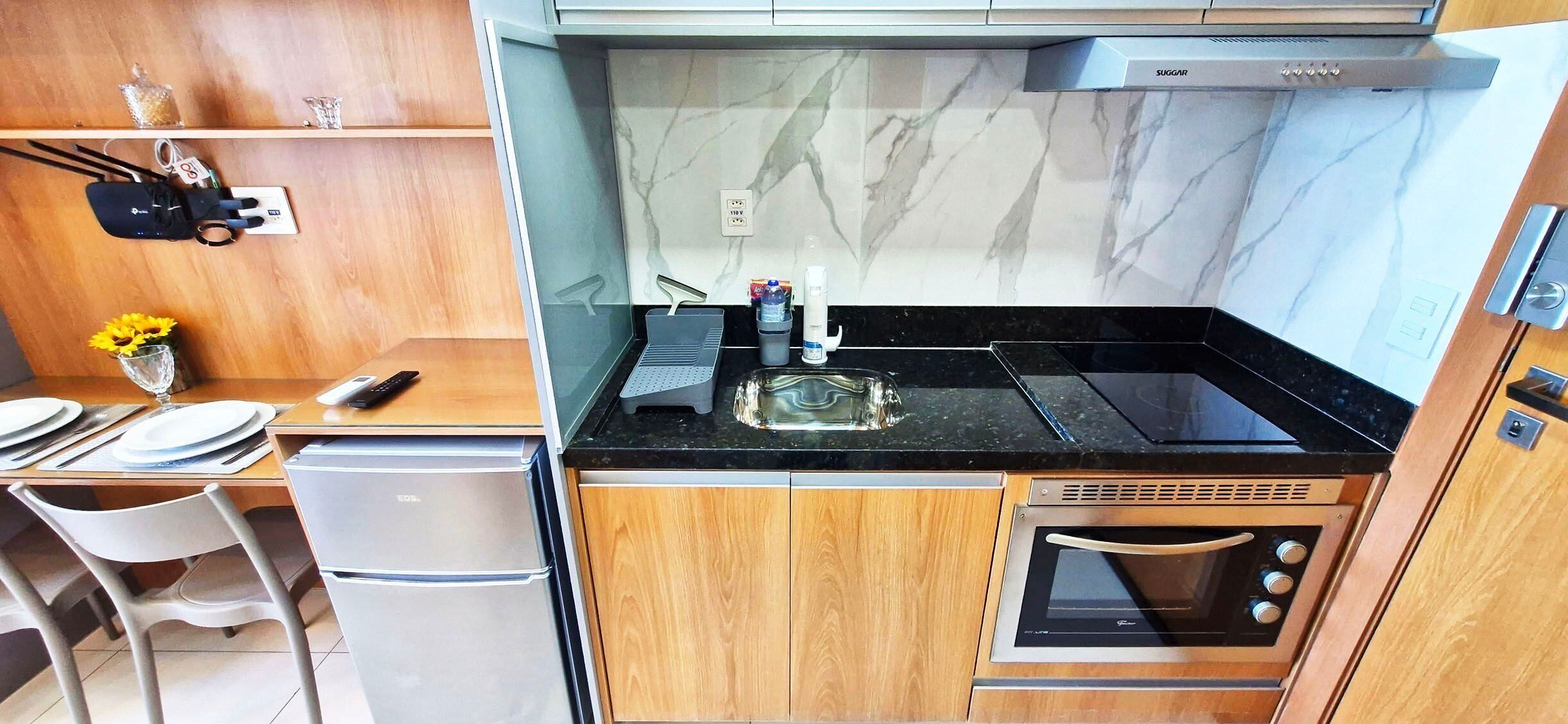 A compact kitchen with a black countertop, a built-in oven, and wooden cabinets.