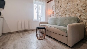 Une pièce chaleureuse avec un mur en pierre, un canapé, une petite table et un radiateur.