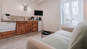 Une cuisine moderne avec des meubles en bois, un lave-vaisselle encastré, une machine à café et un four à micro-ondes. Une grande fenêtre, ornée de rideaux légers, offre une vue sur les arbres à l’extérieur.
