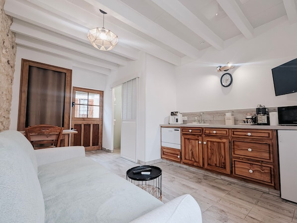 A modern kitchen with wooden cabinets, a built-in oven, and a microwave. There is a dining area with a wooden table and chairs.