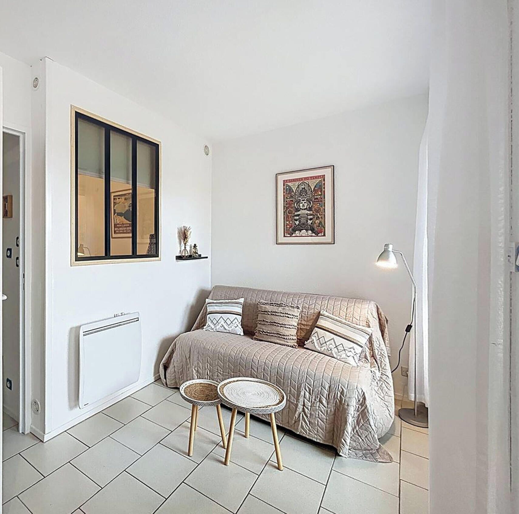 A cozy living room with a sofa, two round tables, and a floor lamp.