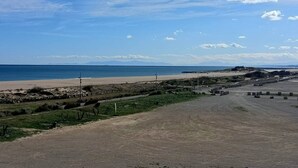 Een kustlandschap met een strand, een zandweg en een parkeerplaats.
