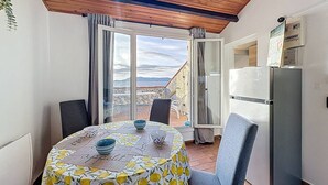 Comedor con mesa lista para dos, refrigerador y vista al campo a través de puertas abiertas.