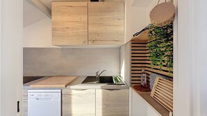 Una cocina compacta con armarios de madera, un lavamanos empotrado y un refrigerador pequeño.
