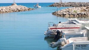 A marina with boats docked, a rocky breakwater, and a lighthouse in the distance. - Apartment in Narbonne, Terrace with Sea View (Narbonne)