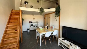 A modern kitchen with a dining area, a TV, and a staircase. - Cozy Nest in Narbonne for 4, near beach, includes parking (Narbonne)