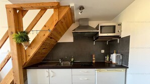 A kitchen with a wooden staircase, a microwave, a sink, and a dishwasher. - Cozy Nest in Narbonne for 4, near beach, includes parking (Narbonne)