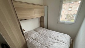 Ein gemütliches Schlafzimmer mit Bett, integriertem Kopfteil, Fenster und Tür.