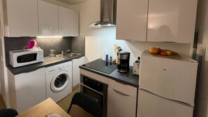 Eine kompakte Küche mit Waschmaschine, Mikrowelle, Toaster und kleinem Kühlschrank.