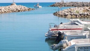 A marina with boats docked, a rocky breakwater, and a lighthouse in the distance. - 2-Star Apartment 50m from Beach with Balconies and Private Parking (Narbonne)