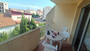 A balcony with a table and chairs, a view of buildings, and a clear sky. - 2-Star Apartment 50m from Beach with Balconies and Private Parking (Narbonne)