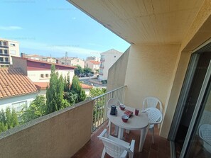 Ein Balkon mit Tisch und Stühlen, Blick auf die Stadt, und ein Gebäude mit rotem Dach.