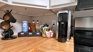 Een keuken met witte kastjes, een houten aanrecht, een koffiezetapparaat en verschillende keukengerei.