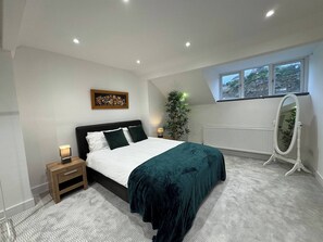 A bedroom with a bed, bedside table, lamp, potted plant, radiator, and a window with a view. - Central 4 bed Home in Ecclesall Near Peaks (Sheffield)