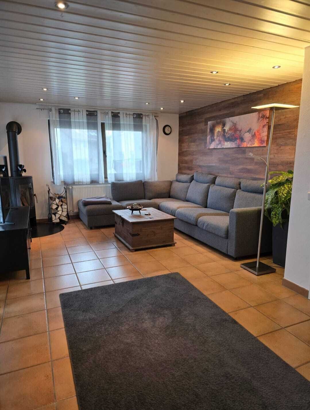 Ein modernes Wohnzimmer mit einem Ecksofa, einem Kamin und einem großen Gemälde an der Wand.